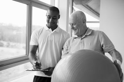 2 men smiling with ongoing training using excersice ball